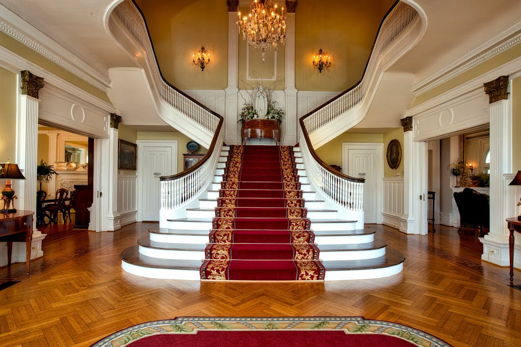 Photo by Pixabay Grand staircase with red carpet in a luxurious hotel lobby, highlighted by a chandelier.
